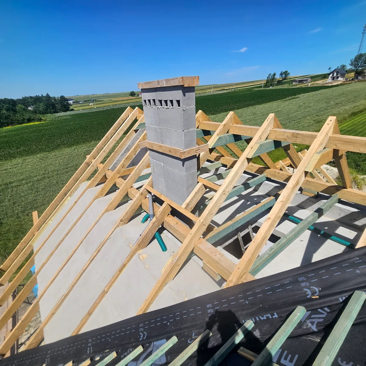 Konstrukcja dachu z drewnianych krokwi i murowanym kominem Dach