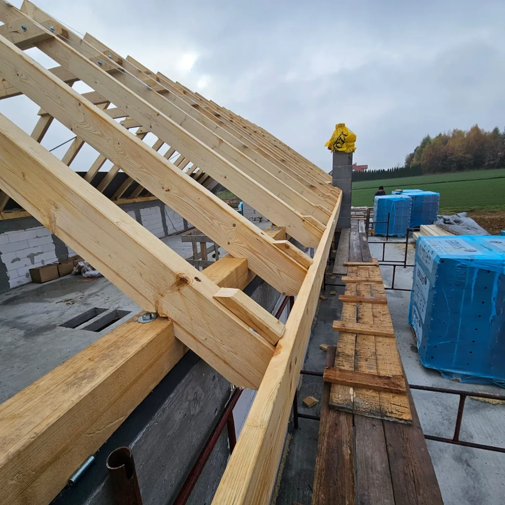 Więźba dachowa montowana na budowie: drewniane krokwie i deskowanie