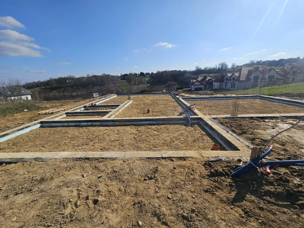 Fundamenty domu – przygotowane betonowe ławy fundamentowe z izolacją i podejściami instalacyjnymi