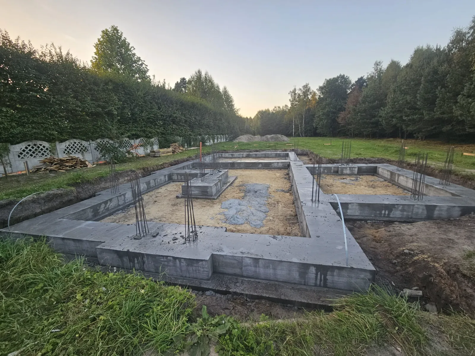 Wykonane fundamenty tradycyjne budynku z betonowymi ławami i pionowymi prętami zbrojeniowymi