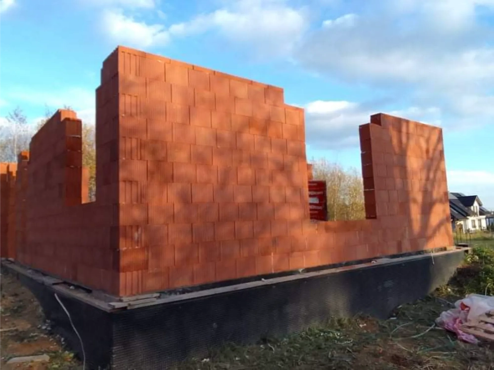 Ceglane ściany stanu surowego osadzone na izolacji fundamentów