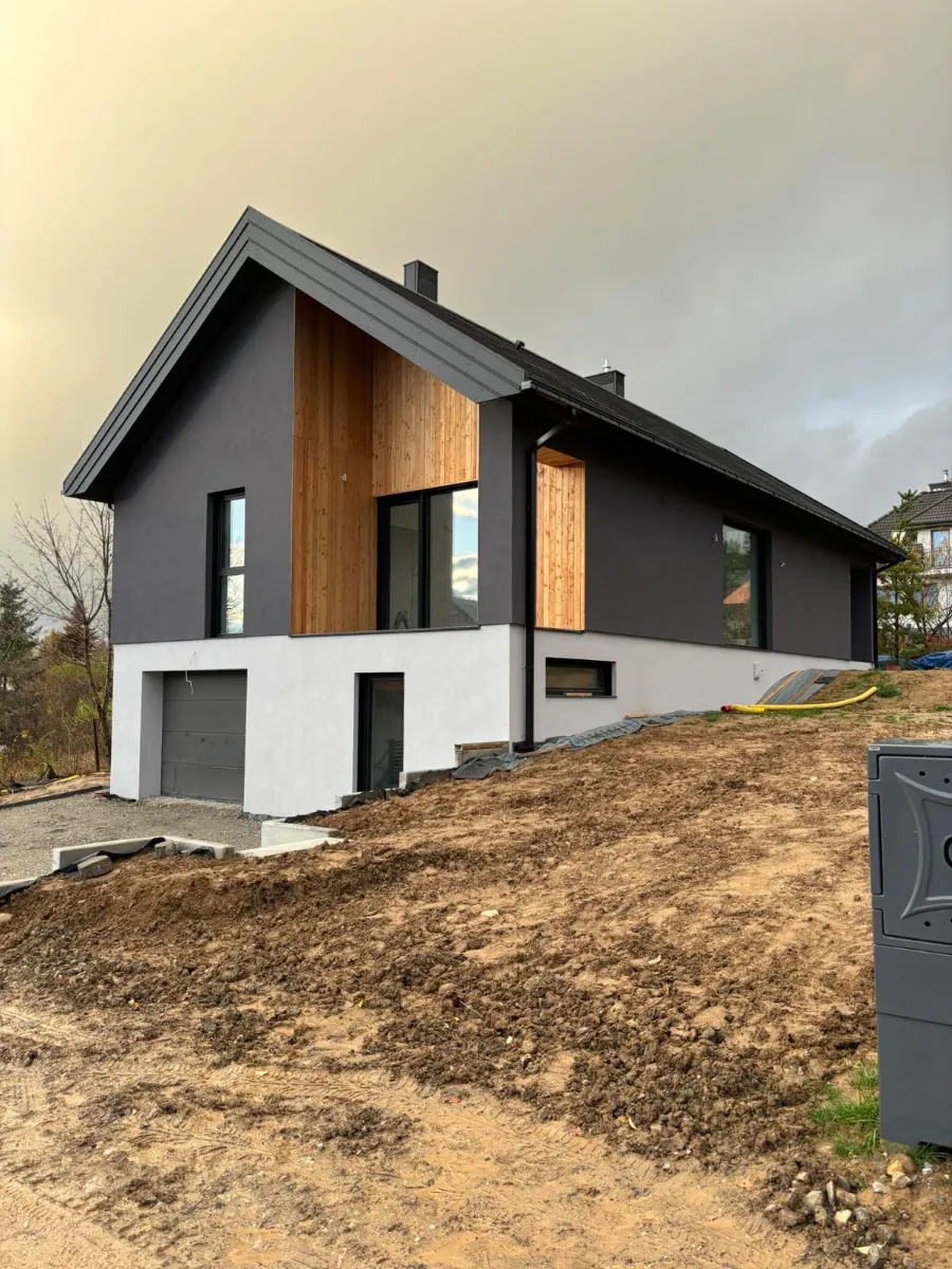 Nowoczesny dom jednorodzinny z czarną elewacją i drewnianymi panelami Elewacje domu