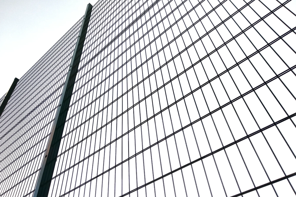 Zbliżenie na ogrodzenia panelowe: stalowe panele zgrzewane zamocowane do słupków